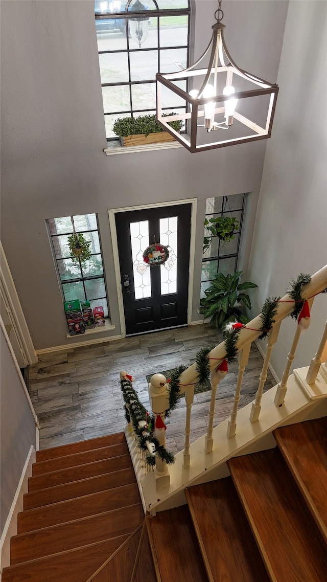 foyer entrance featuring a notable chandelier, plenty of natural light, wood-type flooring, and a towering ceiling