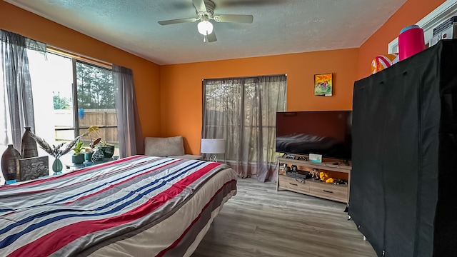 bedroom with ceiling fan, hardwood / wood-style floors, and a textured ceiling