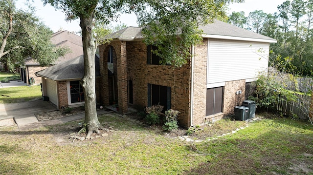 view of side of home with central AC unit, a garage, and a yard