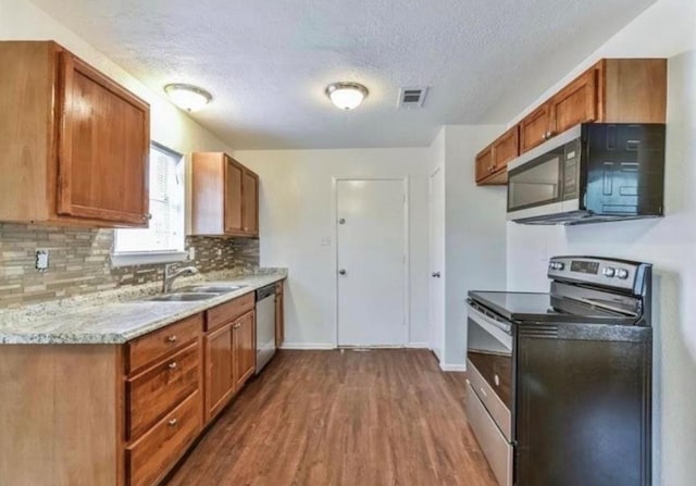 kitchen featuring a textured ceiling, backsplash, stainless steel appliances, and dark wood-type flooring