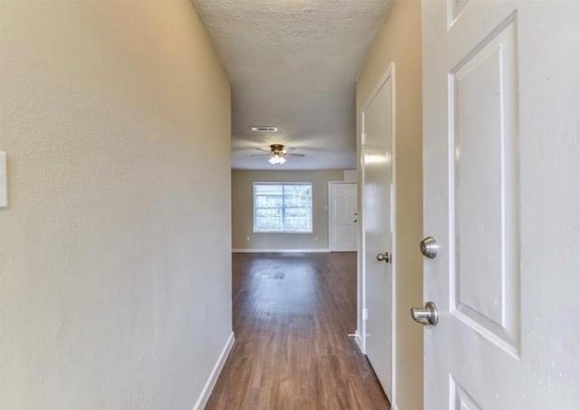 hall with dark hardwood / wood-style flooring and a textured ceiling