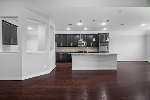 kitchen featuring decorative light fixtures, an island with sink, appliances with stainless steel finishes, and dark wood-type flooring