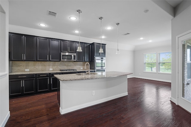 kitchen featuring sink, stainless steel appliances, hanging light fixtures, and a kitchen island with sink