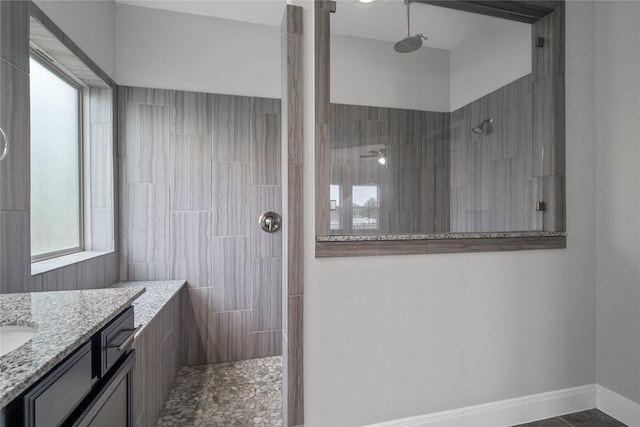 bathroom with tiled shower, vanity, and a wealth of natural light