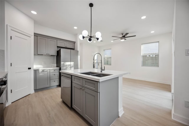 kitchen featuring light countertops, stainless steel appliances, a sink, and gray cabinetry