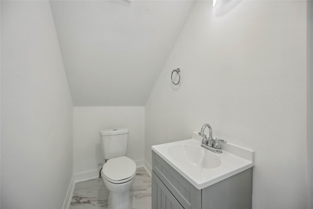 half bath featuring toilet, vanity, baseboards, vaulted ceiling, and marble finish floor