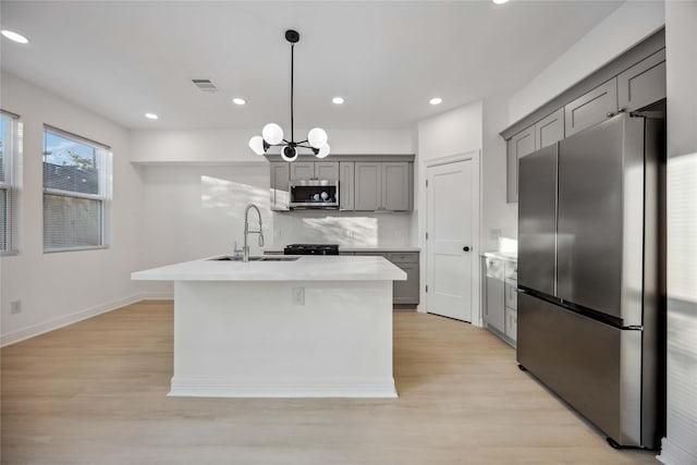 kitchen with appliances with stainless steel finishes, light countertops, light wood-style flooring, and gray cabinetry