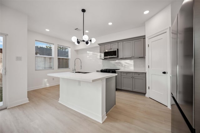 kitchen with tasteful backsplash, gray cabinets, visible vents, appliances with stainless steel finishes, and a sink