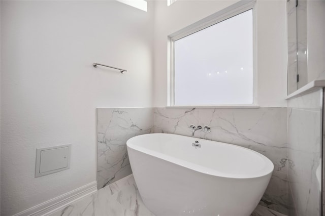 full bath with marble finish floor and a freestanding tub