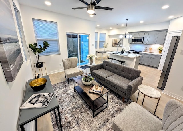 living room with ceiling fan, recessed lighting, baseboards, and light wood-style floors