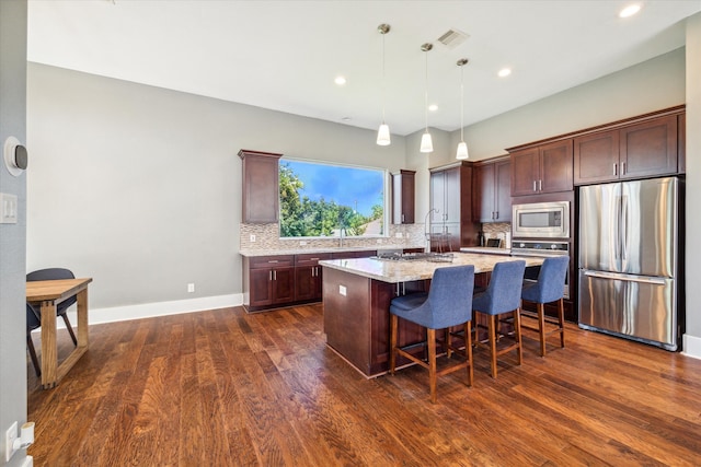 kitchen featuring dark hardwood / wood-style flooring, a center island, decorative light fixtures, and appliances with stainless steel finishes