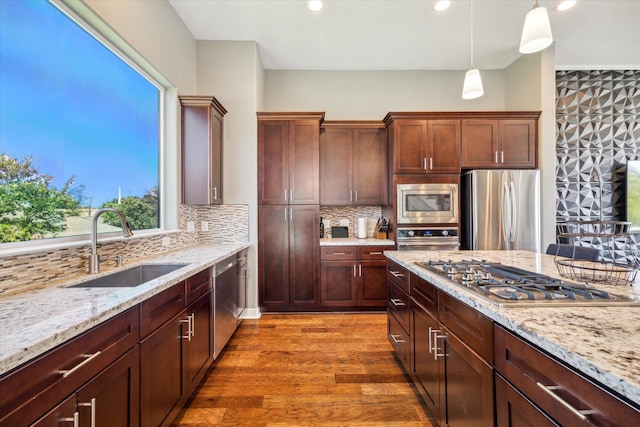 kitchen featuring dark wood-type flooring, sink, decorative backsplash, decorative light fixtures, and stainless steel appliances