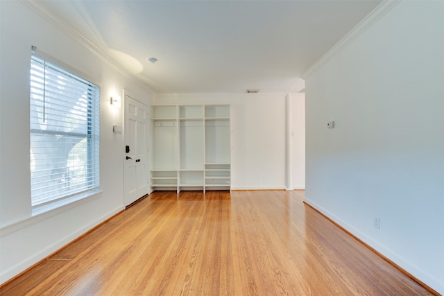 empty room featuring ornamental molding and light wood-type flooring