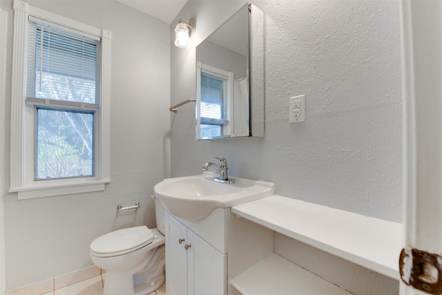 bathroom with tile patterned floors, plenty of natural light, toilet, and vanity