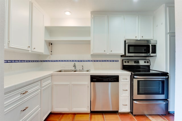 kitchen with white cabinets, sink, decorative backsplash, tile counters, and stainless steel appliances