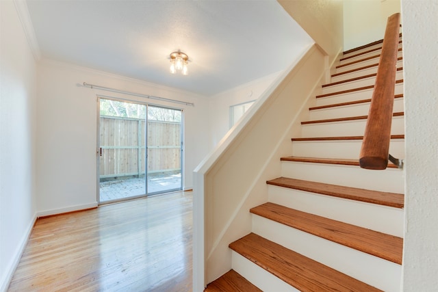 staircase featuring crown molding and wood-type flooring