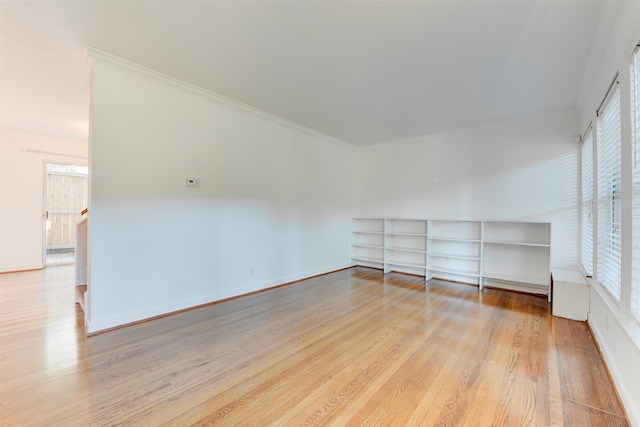 spare room featuring crown molding, a healthy amount of sunlight, and light hardwood / wood-style floors