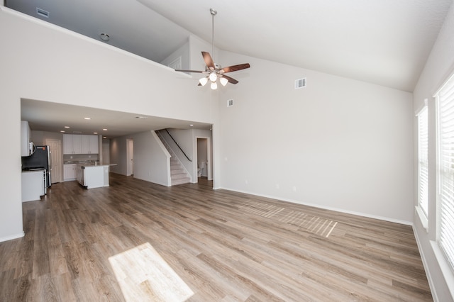 unfurnished living room with ceiling fan, light hardwood / wood-style floors, and high vaulted ceiling