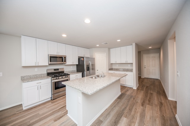 kitchen featuring white cabinets, sink, light hardwood / wood-style flooring, an island with sink, and stainless steel appliances