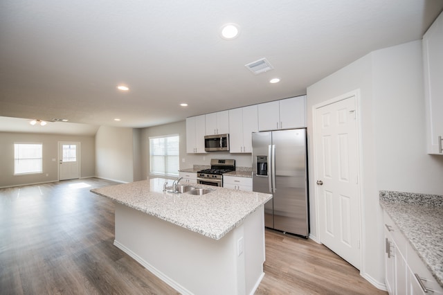 kitchen featuring white cabinetry, an island with sink, stainless steel appliances, and light wood-type flooring