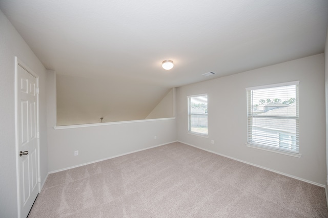 additional living space featuring lofted ceiling and light carpet