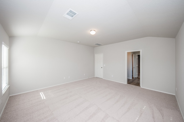 carpeted empty room with vaulted ceiling