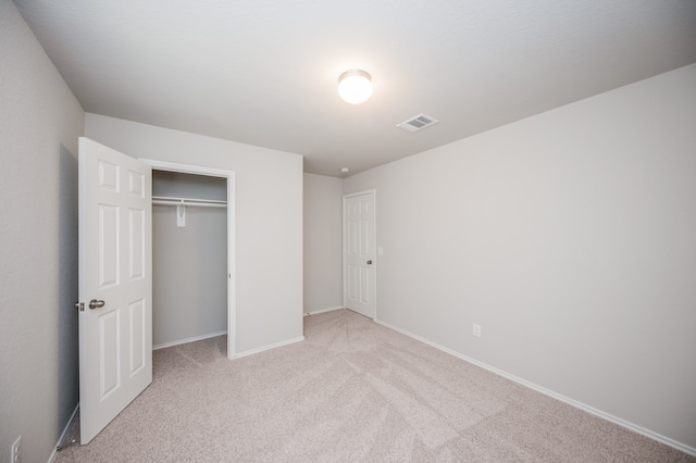 unfurnished bedroom featuring light colored carpet and a closet