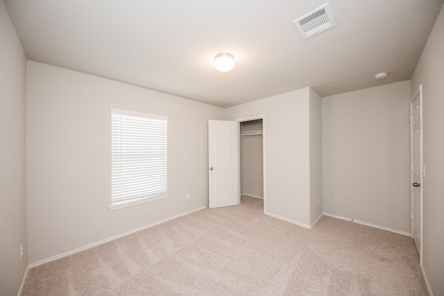 unfurnished bedroom with light colored carpet and a closet