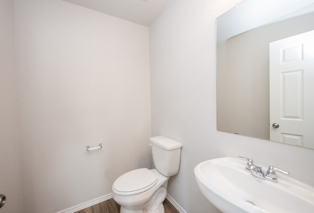 bathroom featuring toilet, wood-type flooring, and sink