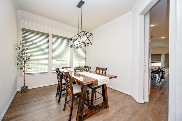 dining space with crown molding, hardwood / wood-style floors, and a notable chandelier