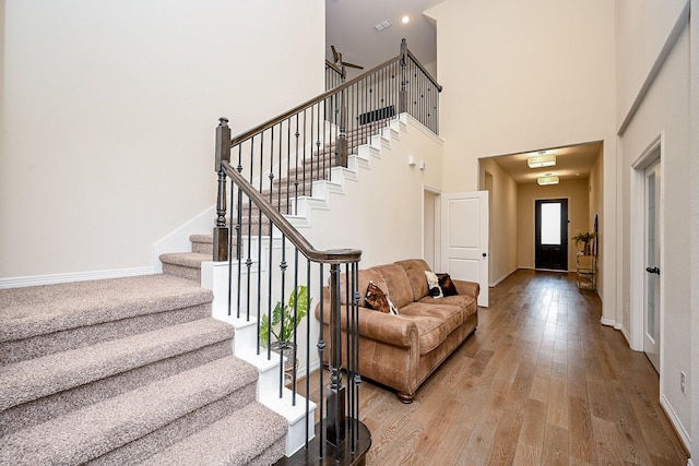 stairway with wood-type flooring and a high ceiling