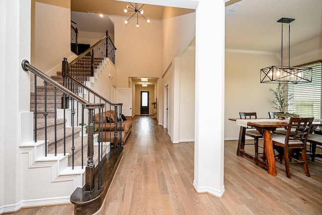 entrance foyer with a chandelier, light wood-type flooring, and ornamental molding