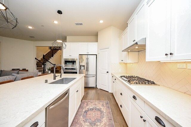 kitchen with white cabinets, sink, hanging light fixtures, appliances with stainless steel finishes, and dark hardwood / wood-style flooring