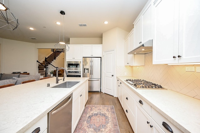 kitchen with hanging light fixtures, white cabinetry, appliances with stainless steel finishes, and sink