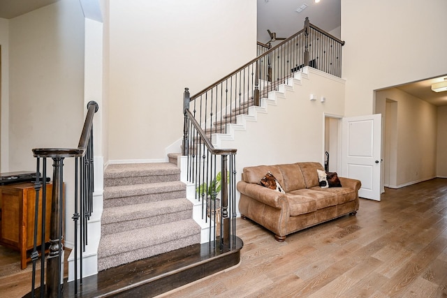 stairs with a towering ceiling and hardwood / wood-style flooring