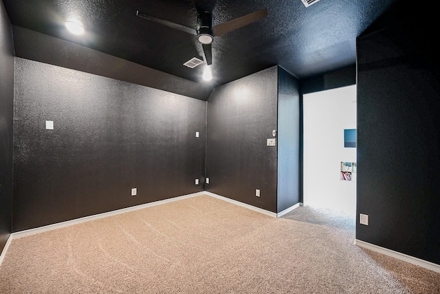 carpeted spare room featuring ceiling fan, vaulted ceiling, and a textured ceiling