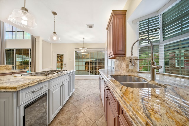 kitchen featuring decorative light fixtures, a healthy amount of sunlight, light stone counters, and sink