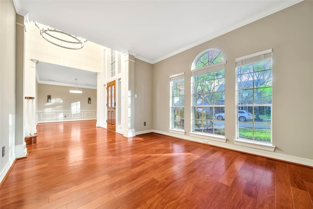 unfurnished living room with crown molding, light hardwood / wood-style flooring, and an inviting chandelier