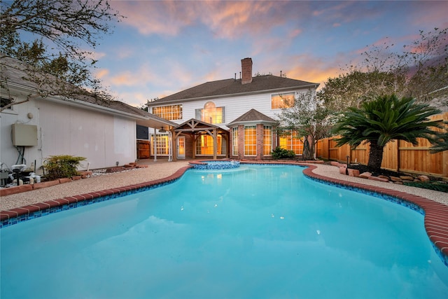 pool at dusk featuring an in ground hot tub and a gazebo