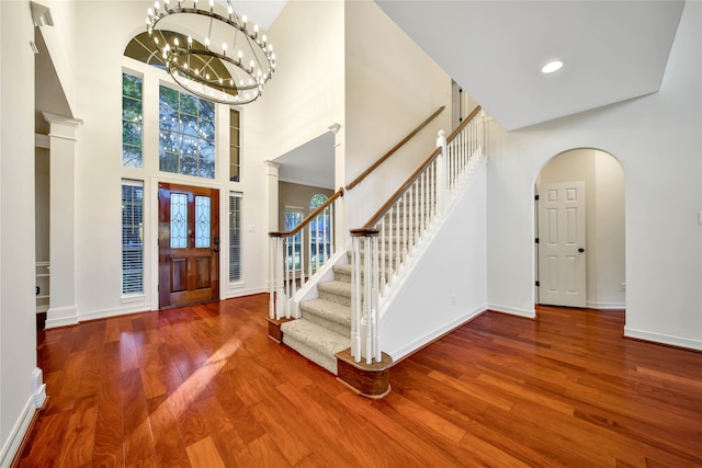 entrance foyer featuring hardwood / wood-style floors, a towering ceiling, and a chandelier