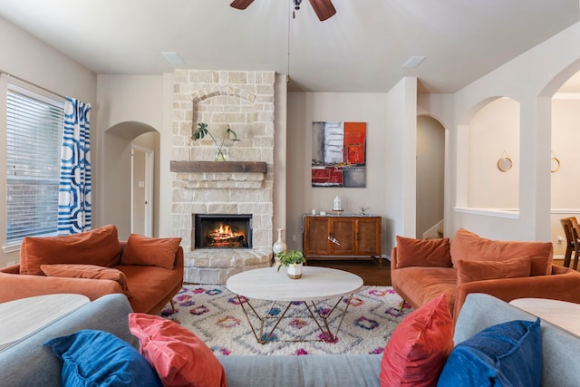 living room featuring ceiling fan, a stone fireplace, and hardwood / wood-style flooring