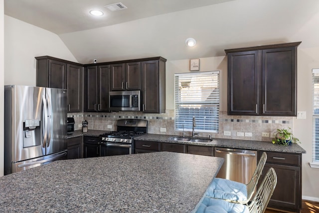 kitchen with stainless steel appliances, lofted ceiling, sink, and backsplash