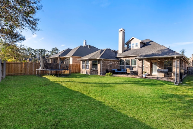 back of house with a lawn, a patio area, and a trampoline