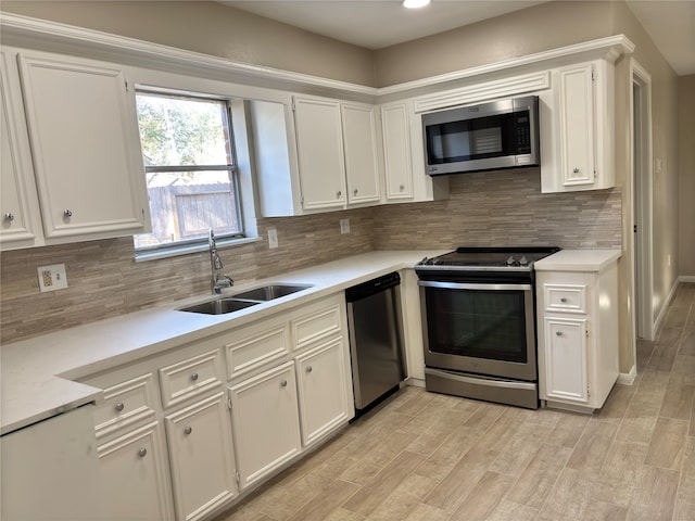 kitchen with backsplash, white cabinets, sink, appliances with stainless steel finishes, and light hardwood / wood-style floors