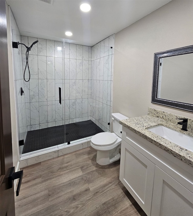 bathroom with hardwood / wood-style floors, vanity, toilet, and walk in shower