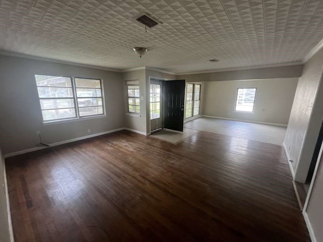 spare room featuring ornamental molding, dark wood-type flooring, and a wealth of natural light