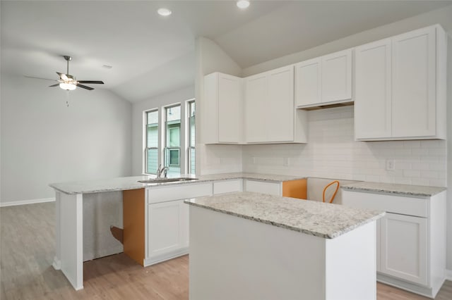 kitchen featuring white cabinetry, a kitchen island, and lofted ceiling