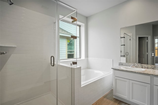 bathroom with hardwood / wood-style flooring, vanity, and independent shower and bath