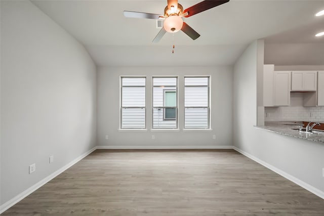 empty room featuring hardwood / wood-style floors, vaulted ceiling, ceiling fan, and sink