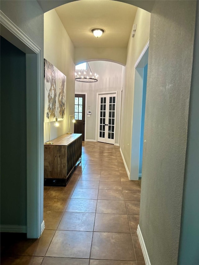 hall with french doors, a chandelier, and tile patterned flooring